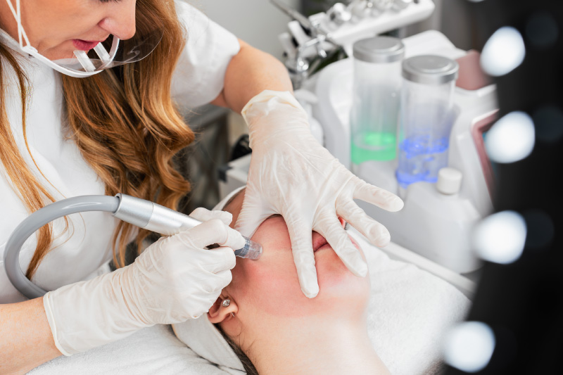 Aesthetic provider using a facial infusion device on a patient during a peptide-based skincare treatment.