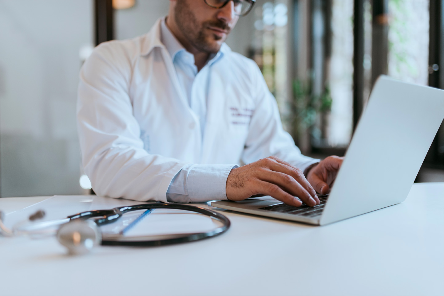 Men’s health clinic provider managing electronic records and insurance tasks in a professional setting.